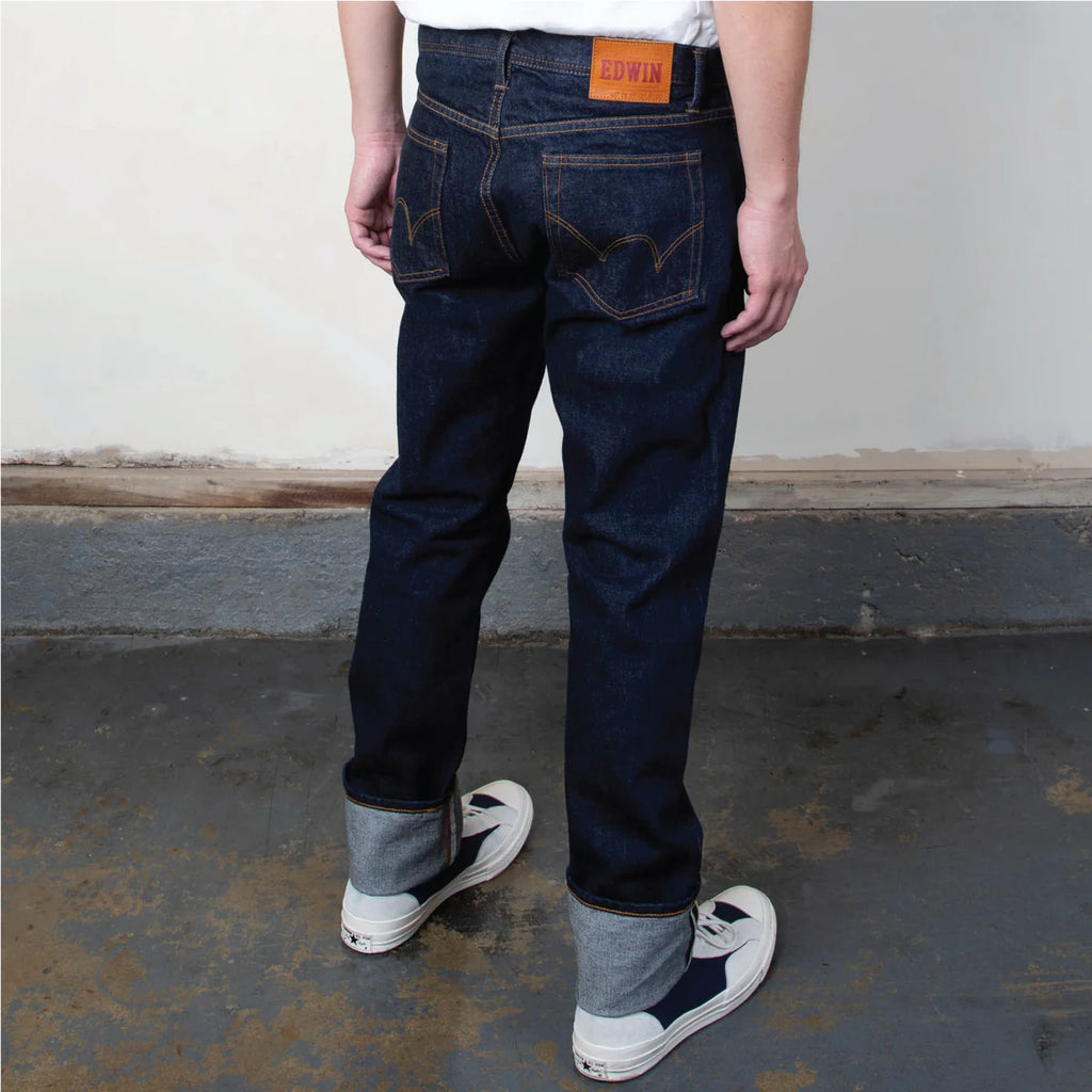 Person wearing dark blue jeans with a visible brand label, standing on a concrete floor.