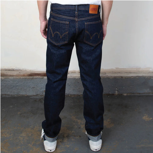 Person wearing dark blue jeans with a visible Levi's logo on a plain background