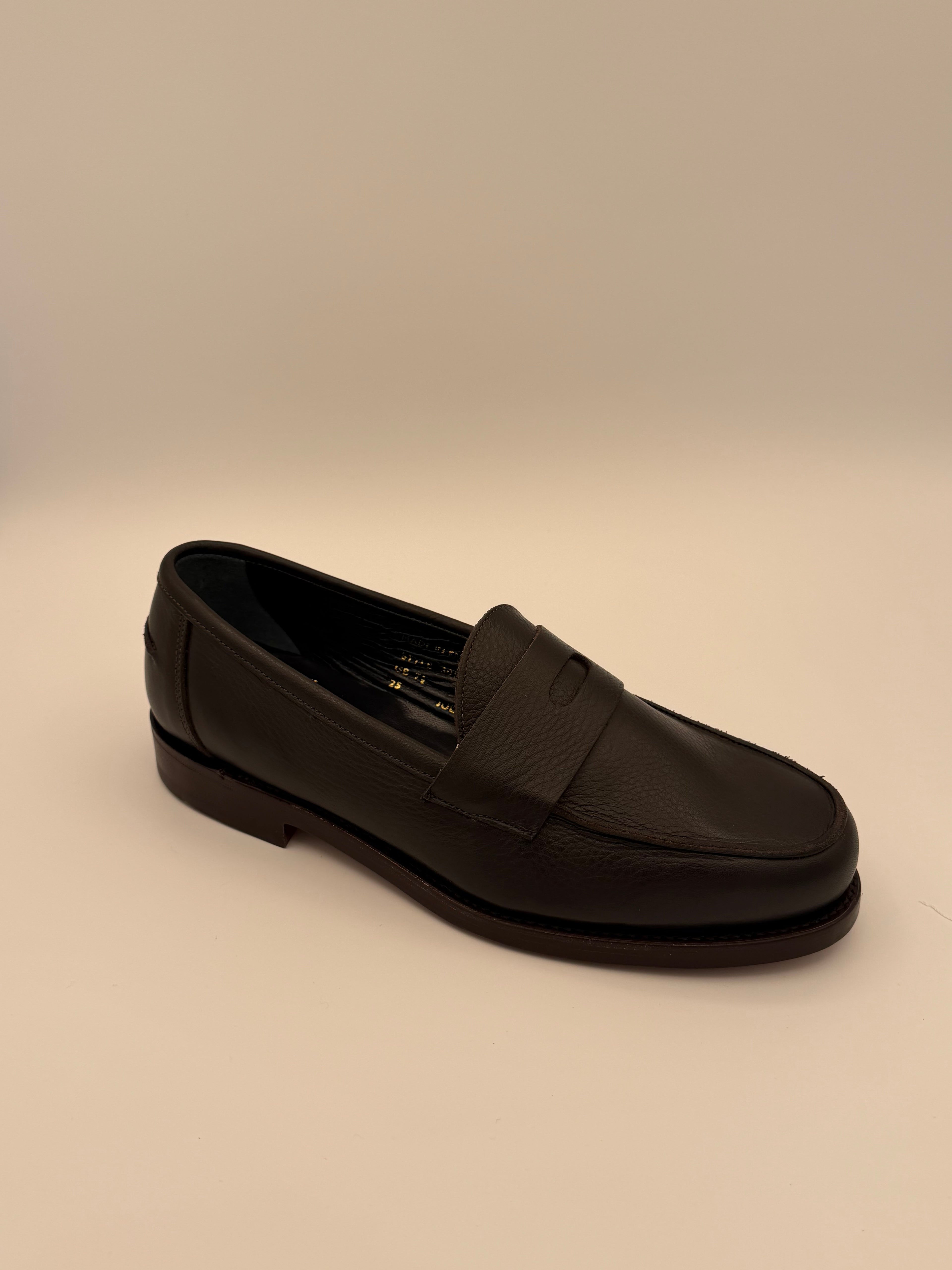 Black loafer shoe on a beige background