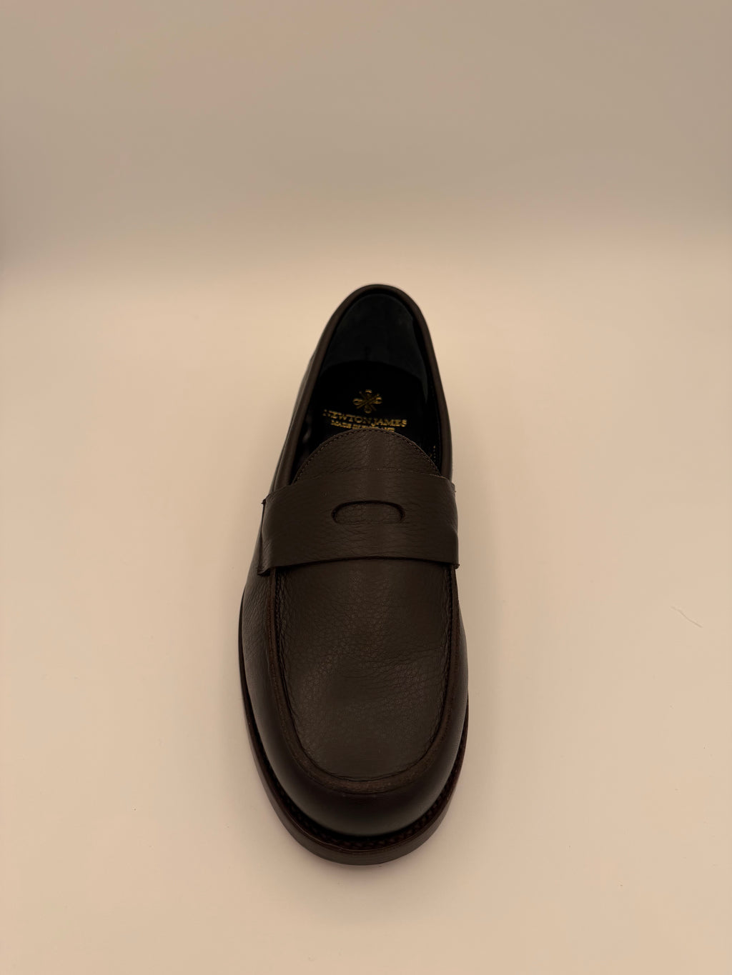 top view of Black leather shoe on a beige background