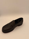 side view of Black leather shoe on a beige background