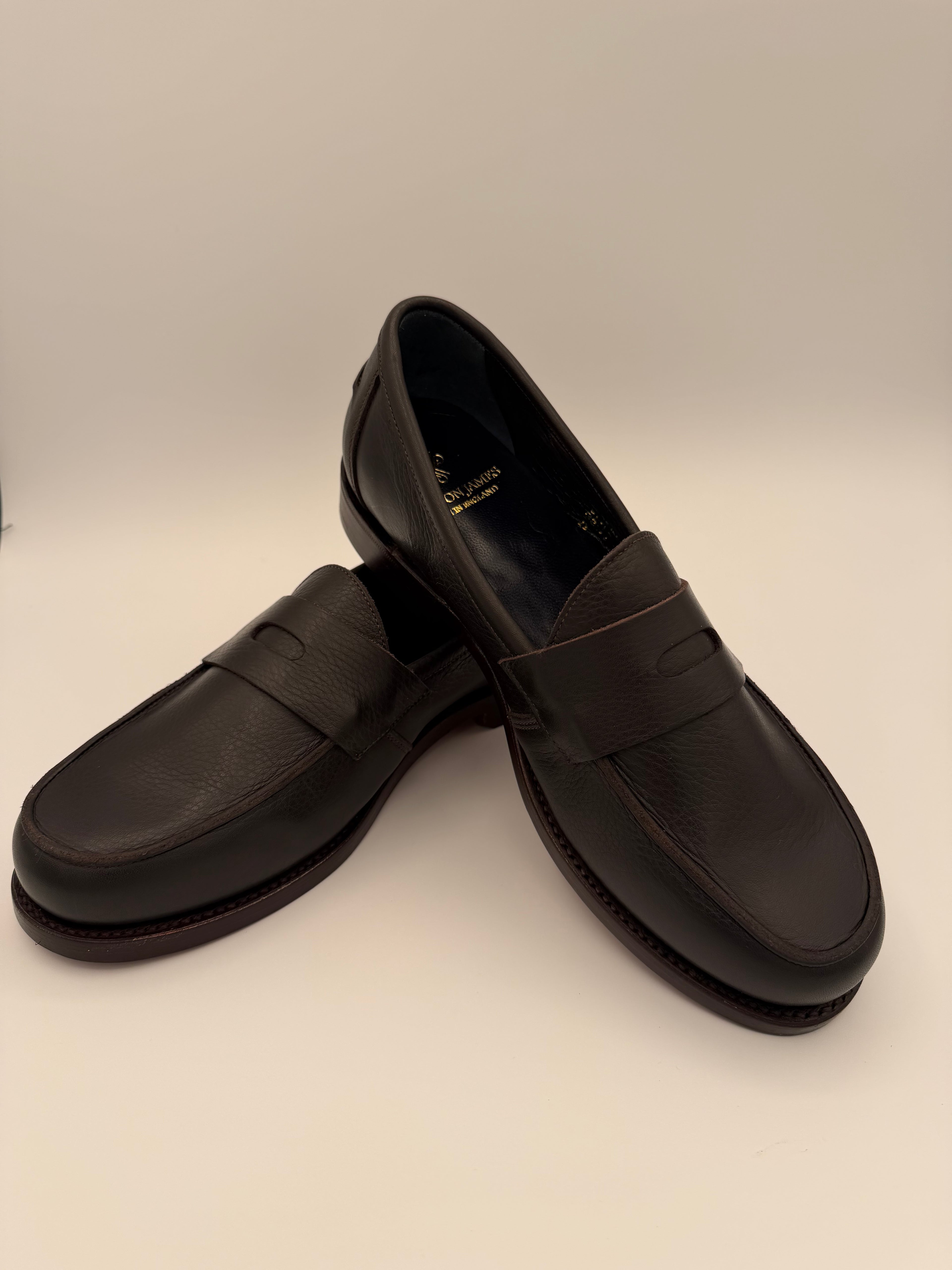 Pair of black loafers on a light beige background