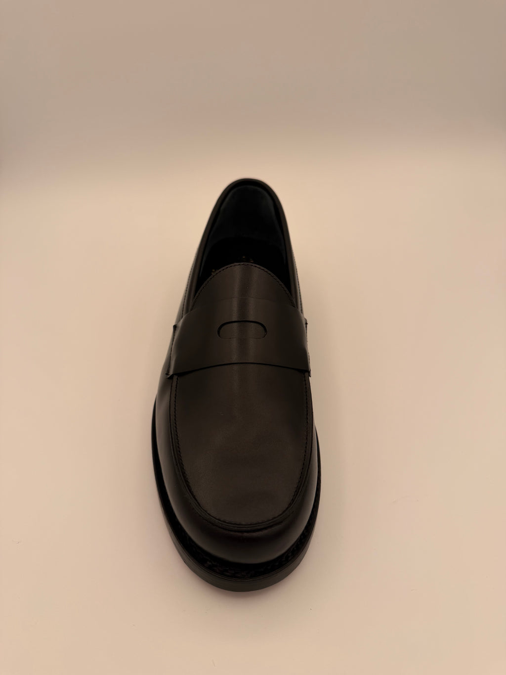 Forward facing Black shoe on a beige background
