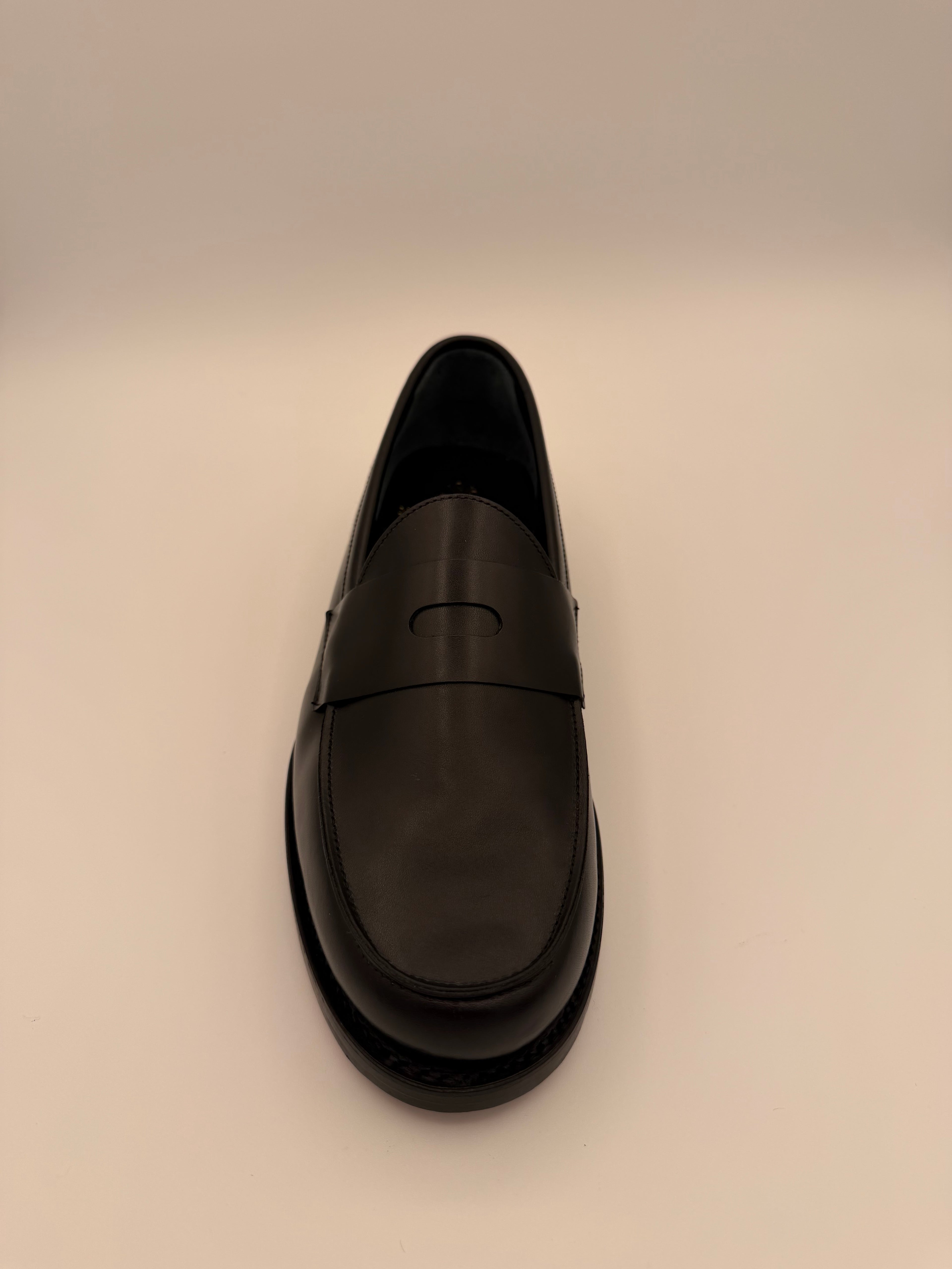 Forward facing Black shoe on a beige background