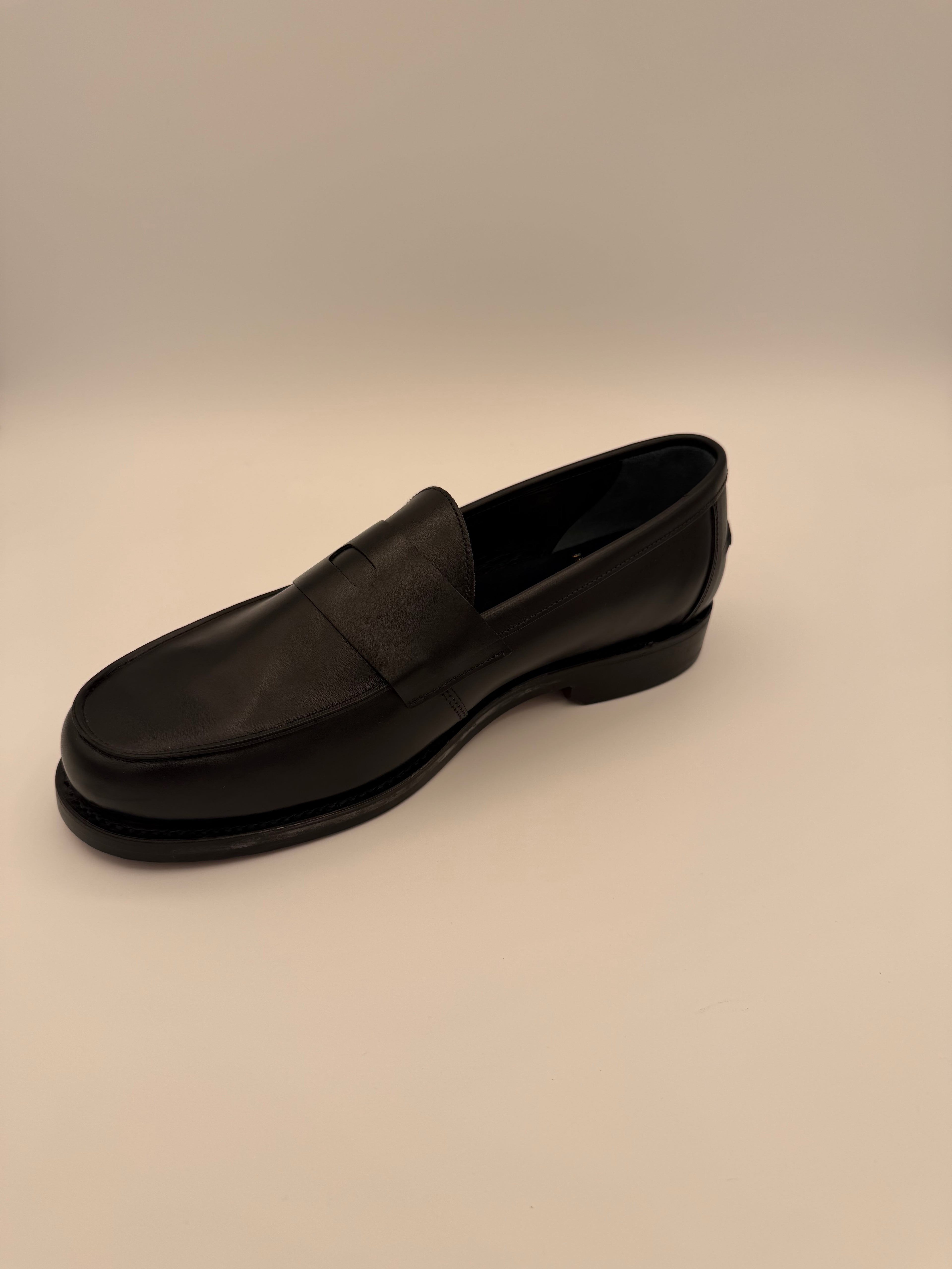 side view of Black shoe box on a beige background