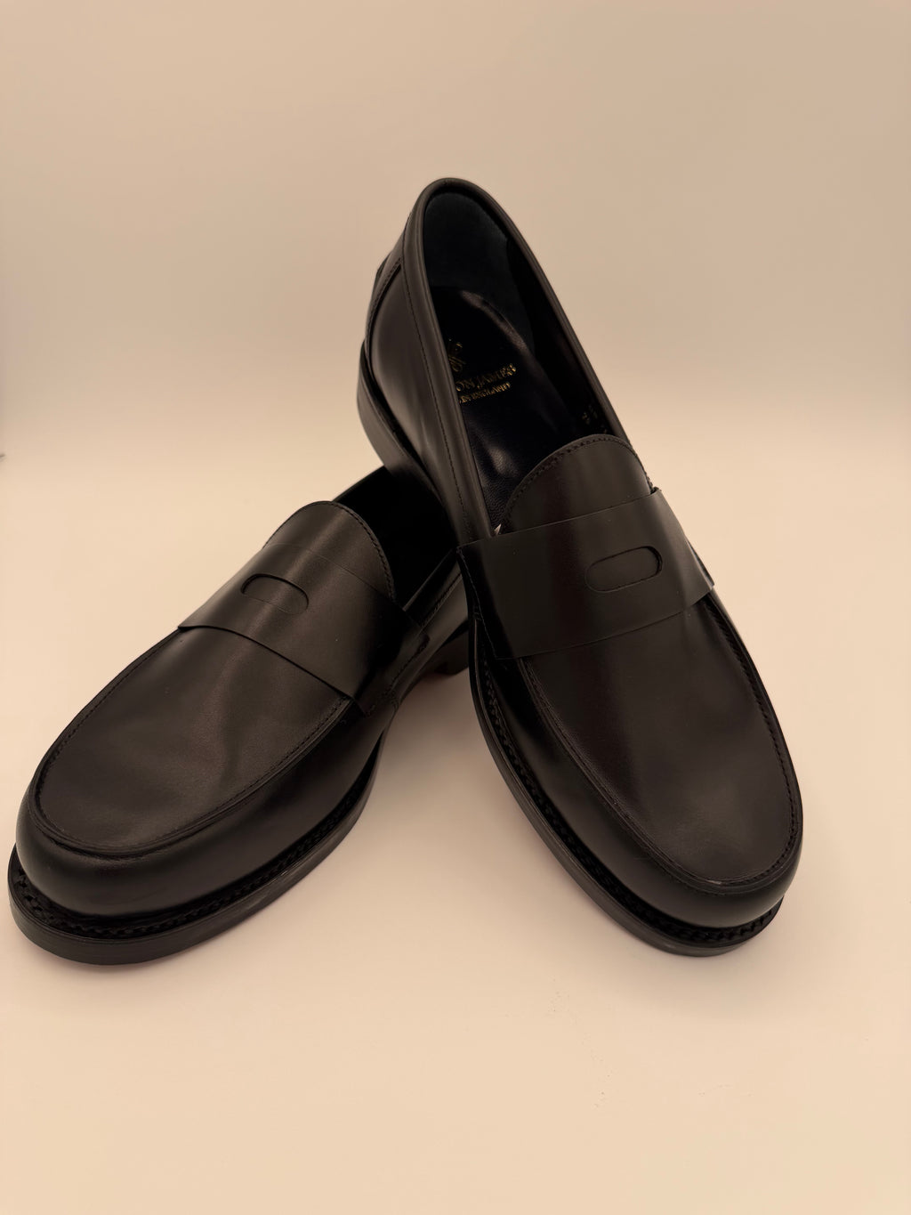 Pair of black loafers on a beige background