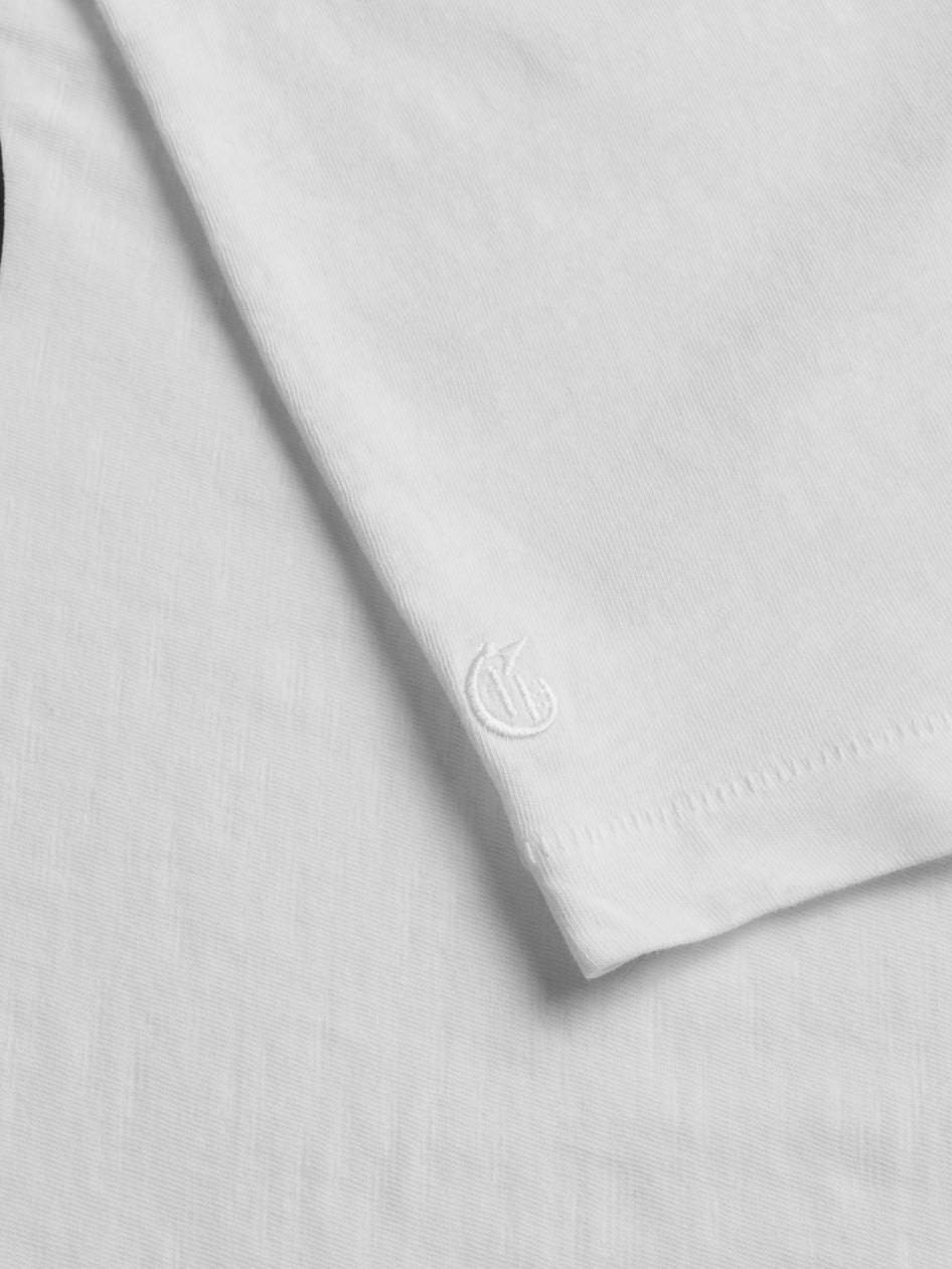 Close-up of a white t-shirt with a brand logo on a light gray background