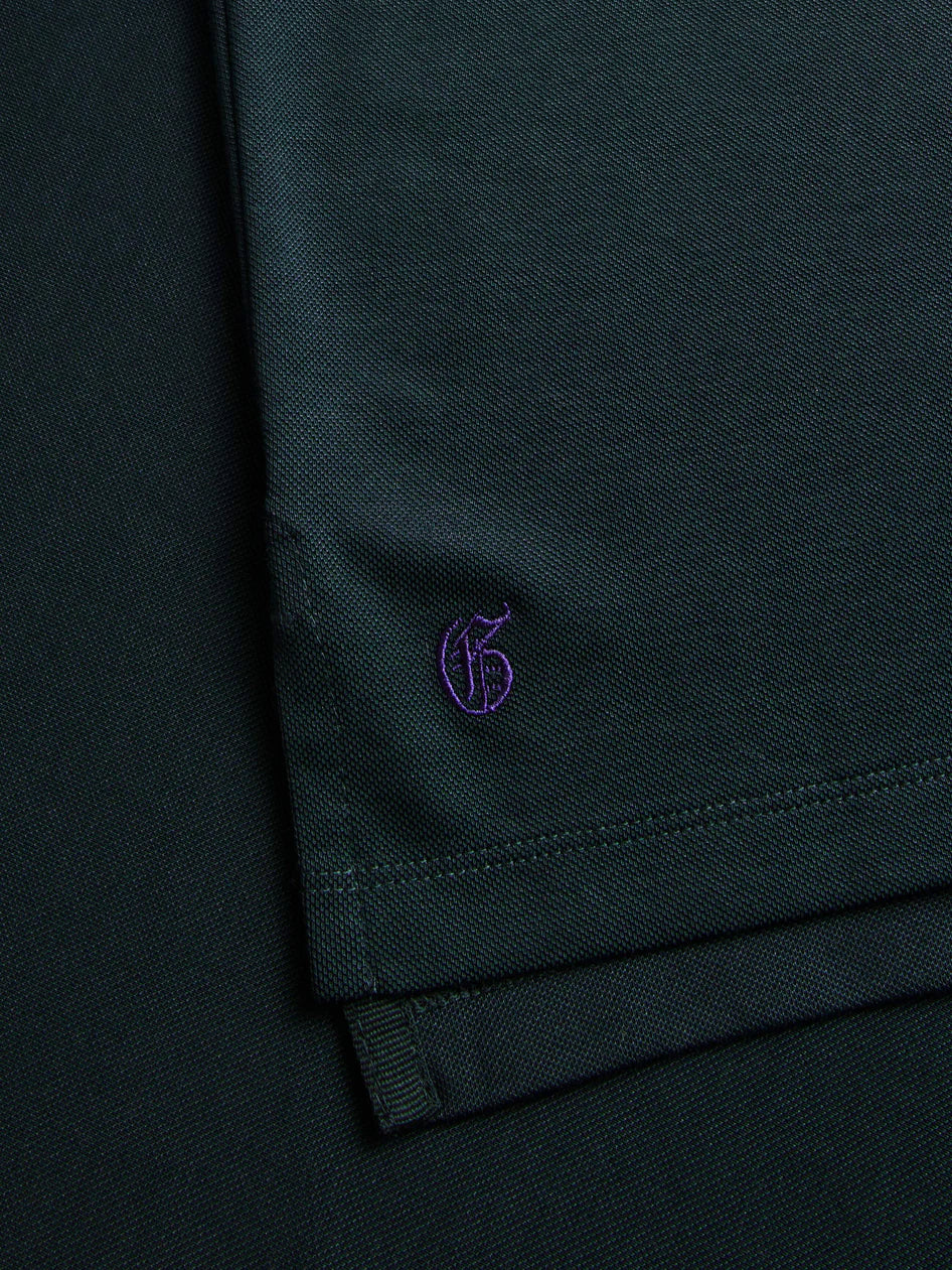 Close-up of a dark green fabric with a small logo on a dark background