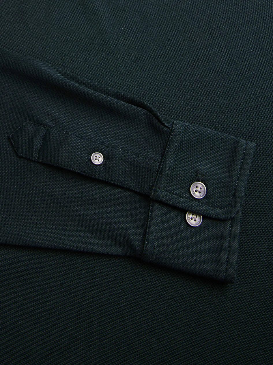Close-up of a dark green shirt with buttoned cuffs on a matching background