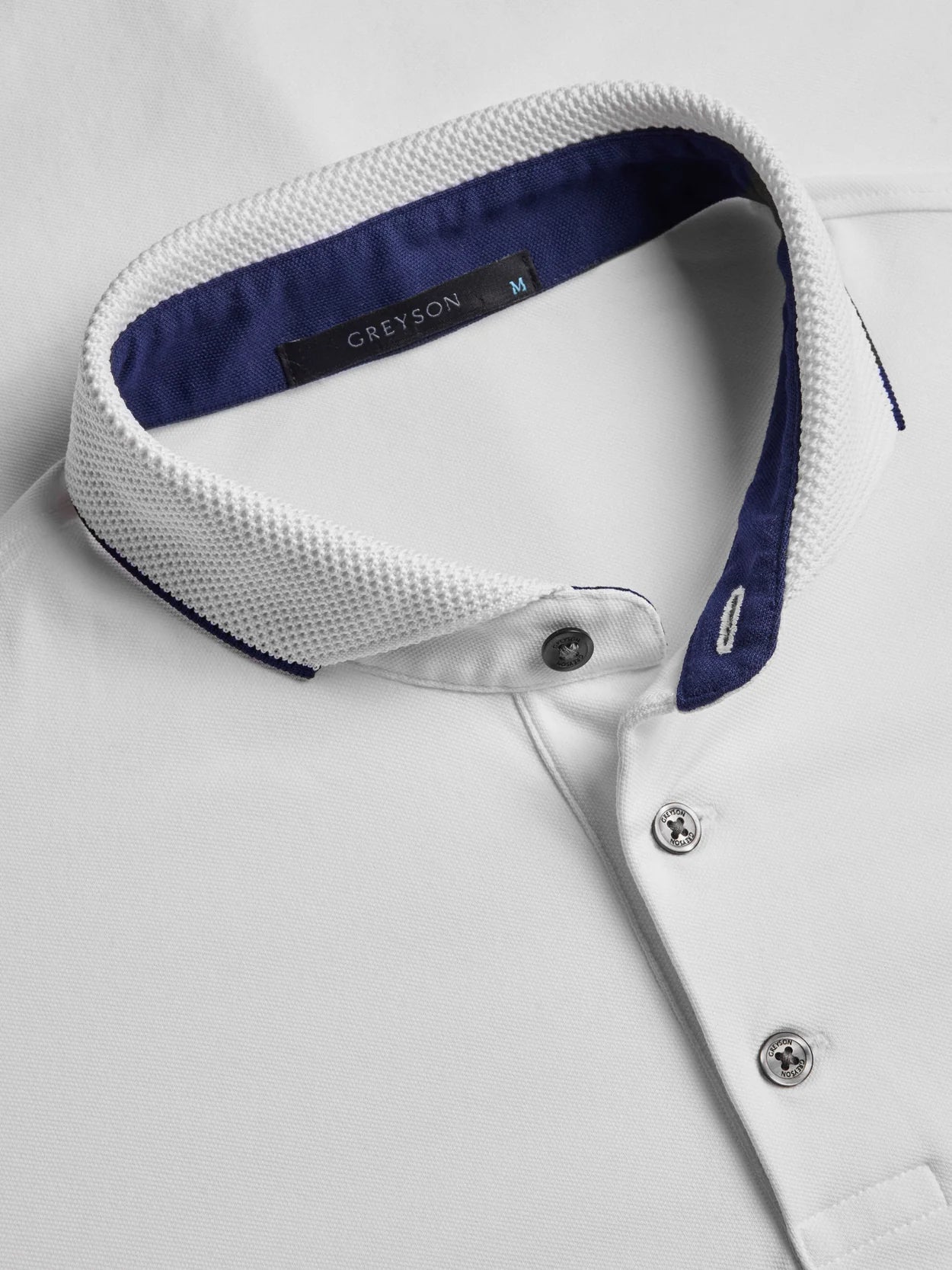 Close-up of a white shirt with a blue collar and 'GREYSON' label.